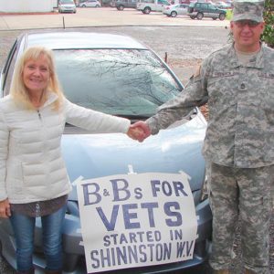 veteran couple in front of car