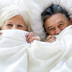 Couple in bed giggling with sheets pulled up, bnbfinder bed and breakfast directory