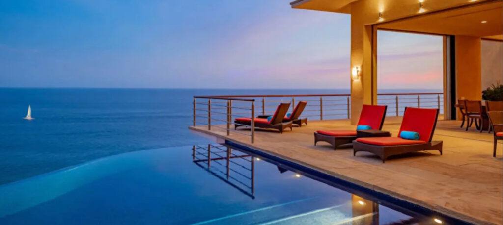 Graphic slider of ocean and deck overlooking the ocean with red chairs.